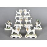 Four pairs of continental flatback porcelain poodles, each modelled standing with baskets of flowers