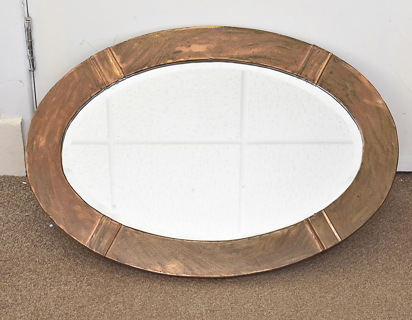 An arts and crafts copper oval framed mirror, with planished decoration, 68 cm x 47 cm