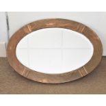 An arts and crafts copper oval framed mirror, with planished decoration, 68 cm x 47 cm