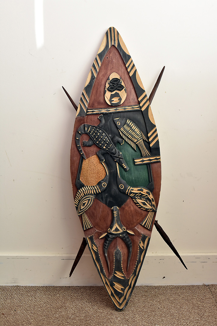 A contemporary Zambian carved bark shield, with carved hardwood spears verso, decorated with animals