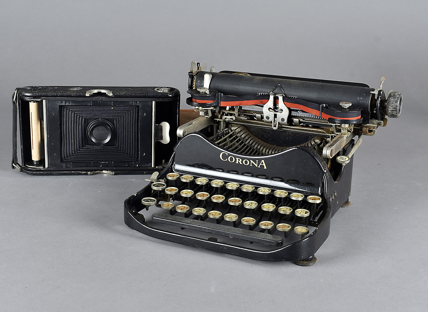 A folding Corona typewriter, with QWERTY keyboard in black enamel together with an Ensign