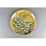 A Linthorpe pottery charger, decorated with wild orchids against a mustard ground, impressed mark to