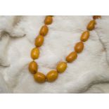 An Art Deco period amber bead necklace, graduating oval shaped beads, ranging from 15mm to 22mm, 88g