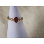 A modern 9ct gold and gem set ring, having a pear shaped rubelite flanked by a pair of small