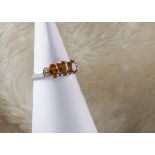 A modern 9ct white gold three stone spessartite dress ring, heightened by diamond set shoulders, 2.