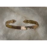 An early 20th century 9ct gold torsion bangle, with textured ground and raised leaf decoration