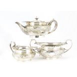 An Edwardian silver three piece tea set by Elkington & Co, squat form with ornate shell, mask and