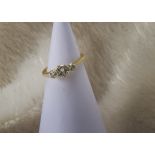 An 18ct gold and three stone diamond ring, having a larger central and two small brilliant cuts in