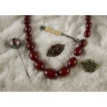 An Art Deco cherry amber style bead necklace, together with a silver and paste set hatpin, AF, a