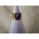 A retro 9ct gold and amethyst dress ring, the raised collet setting housing a cabochon domed