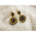 A pair of Victorian pendant earrings, the gilt metal roundels each supporting a cabochon red garnet,