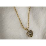 A Middle Eastern yellow metal necklace and pendant, the heart shaped pierced pendant set with