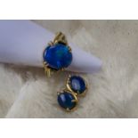 An 18ct gold opal and diamond dress ring and earrings, the large blue tinged oval stone flanked by a