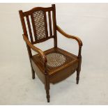 An Edwardian caned commode bedroom chair, with ceramic bowl and cover