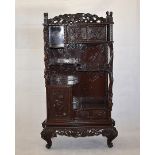 A Meiji Period Japanese hardwood cabinet, having carved design throughout, the top cupboard with