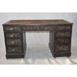 A Victorian carved oak pedestal desk, with nine graduated drawers with lion-mask pulls, on