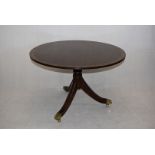 A mahogany and satinwood hall table, having circular top, on tripod base, with brass paw casters,