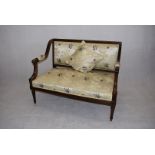 An early 20th Century two seater settee, having carved decoration to the frame, upholstered in