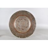 A middle eastern copper charger, decorated with stylised flowers and sunken centre, 39 cm diameter