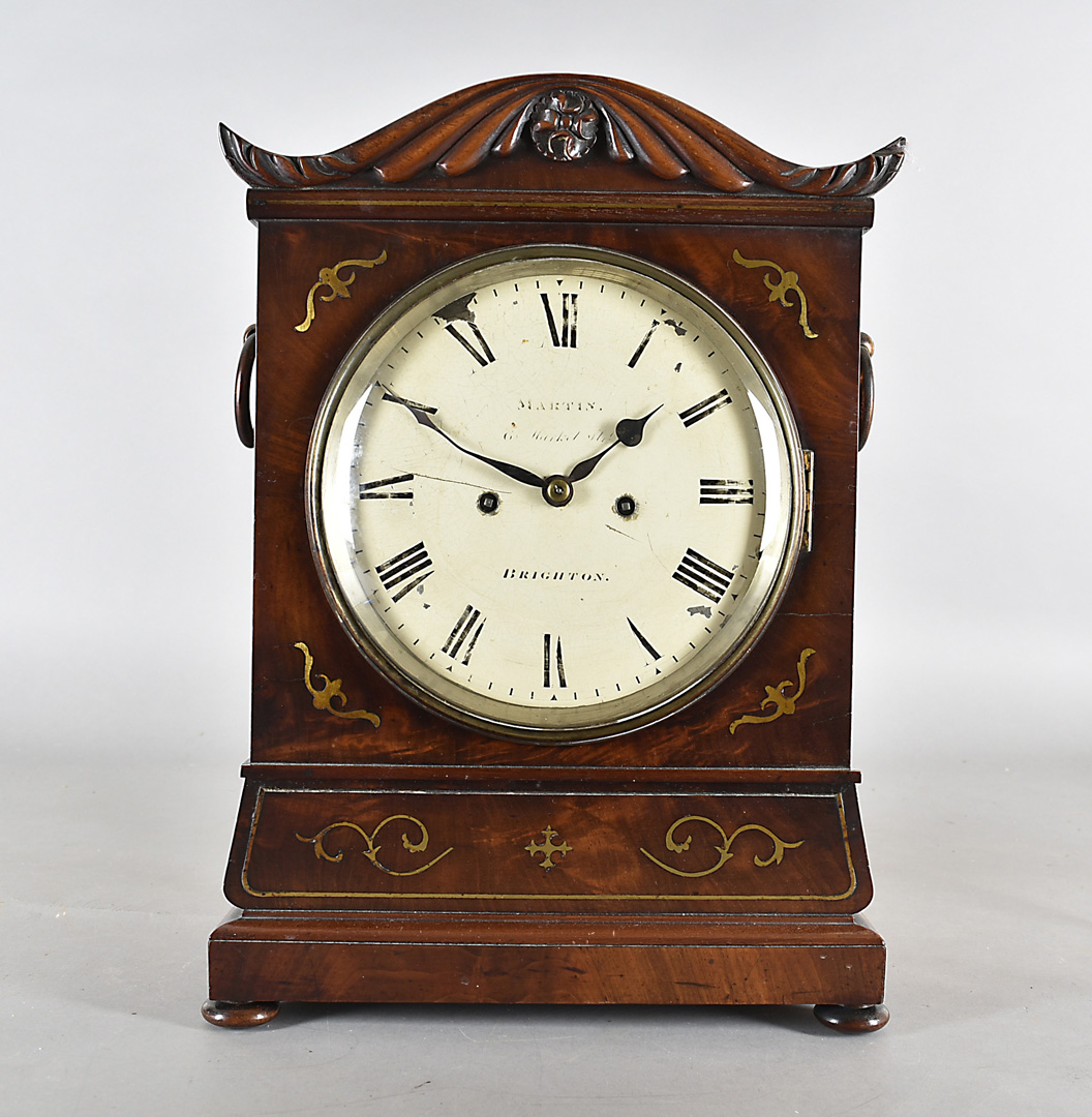 A William IV mahogany eight day mantel clock, with brass inlay, domed top with carved arch inlaid