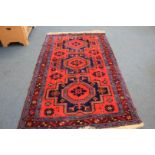 A late 20th century Kazak woollen rug, central panel in red , blue and yellow, 230 cm x 137 cm