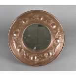 An arts and crafts copper and bevelled glass wall mirror, of circular form with hand made brass