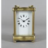 An early 20th century brass carriage time piece, shaped outline, white enamel face and Roman