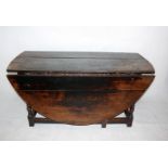 An 18th century oak long drop gate leg table on early refectory style base, with end drawer oval top