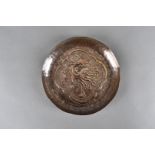An arts and crafts copper hammer beaten dish, centre decorated with mythical beast within quatrefoil