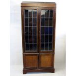 An early 20th century oak glazed book case, panel doors above a pair on panel doors, 86 cm wide x 29