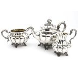 A William IV silver three piece tea set by RA WS, melon shaped with acanthus leaf handles, on scroll