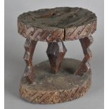 A carved West African hardwood stool, on a three stem support united by an oval pedestal, the top