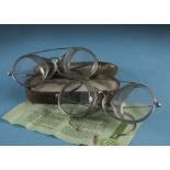 Two pairs of vintage motoring or motorcyle glasses, both with side grills, together with a 1957