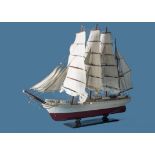 A kit built model of a Scandanavian tall ship, having white and red hull with detailed rigging and