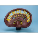 A vintage cast iron tractor seat by Nicholsons of Newark, painted maroon with yellow lettering,