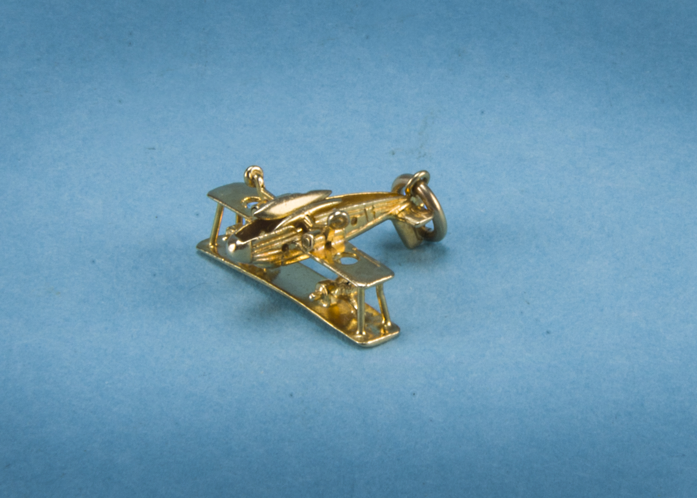 A 1970s 9ct gold aviation interest charm, modelled as a water bi-plane with folding floats under