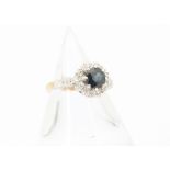 A modern 18ct gold and gem set cluster ring, centred with a blue sapphire dublet stone within border