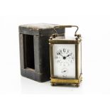 An Edwardian period brass carriage time piece, presented in a travel case, the clock having enamel