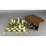 An alabaster chess board with pieces, in a mahogany box with green felt interior, together with a