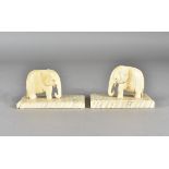 A pair of carved ivory elephants on fossilised mammoth tooth bases, 5.8 cm high (2)