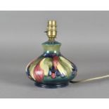 A Moorcroft pottery squat onion shaped lamp base by Walter Moorcroft in 'grape and leaf' pattern,