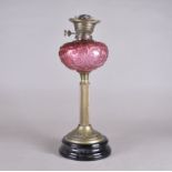 A Victorian cranberry glass oil lamp base, reservoir with scroll decoration, fluted brass stem,