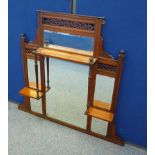 An Edwardian walnut overmantle mirror, six bevelled mirror panels, three gallery shelves, pierced