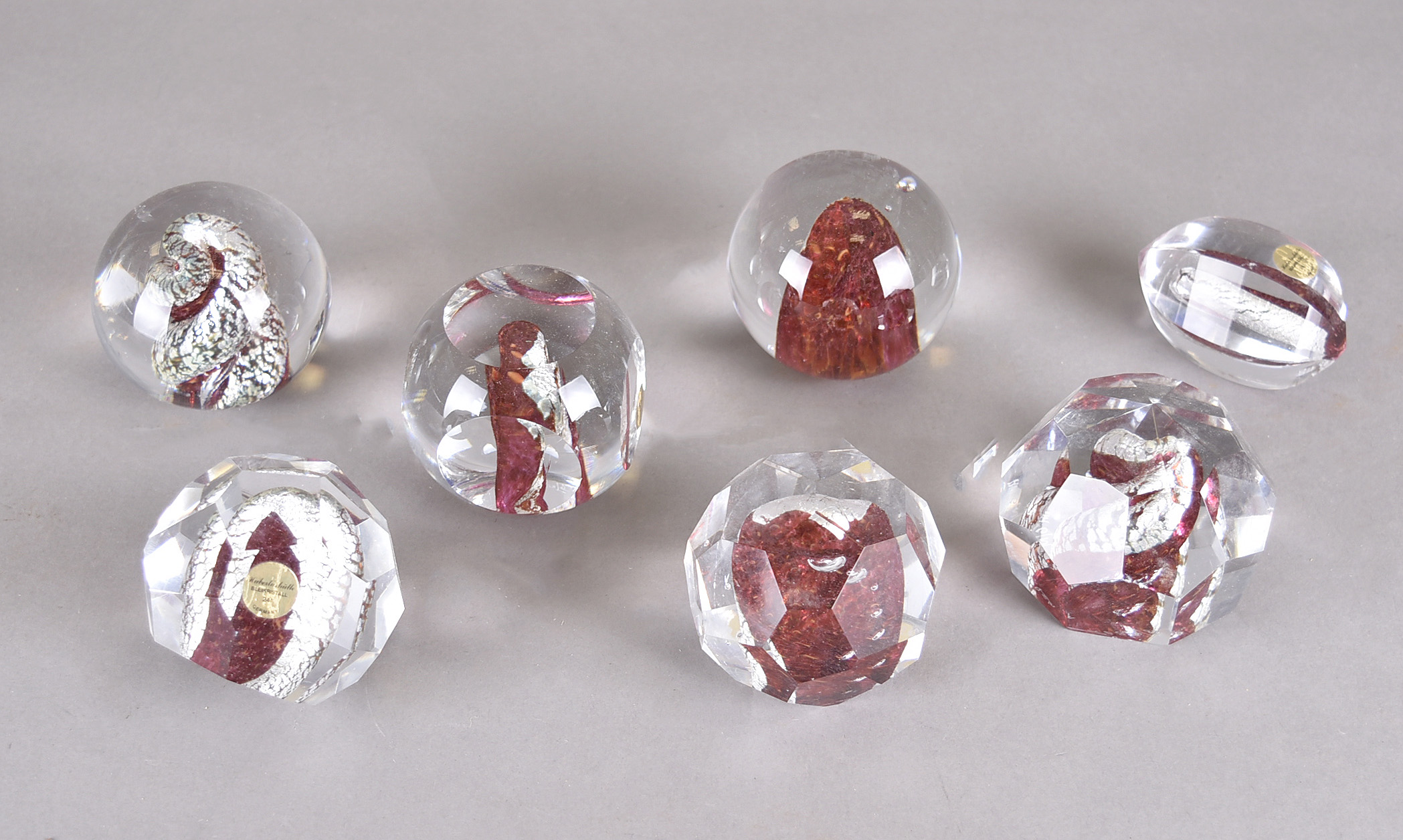 A group of seven lead crystal paperweights by Hubertushütte with silver and granulated red