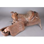 A leather Texan saddle, tooled decoration of stylised flowers, leaves, matching stirrups and sheep