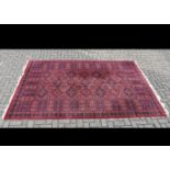 A Turkmen woollen rug, red field with terracotta and indigo lozenge decoration, geometric borders,