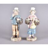 Two continental pottery figures, man and woman, both with umbrellas, wearing hats, painted in