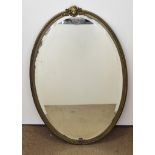 An oval Victorian brass framed mirror with bevelled glass surmounted with lion mask, 85 cm x 55 cm