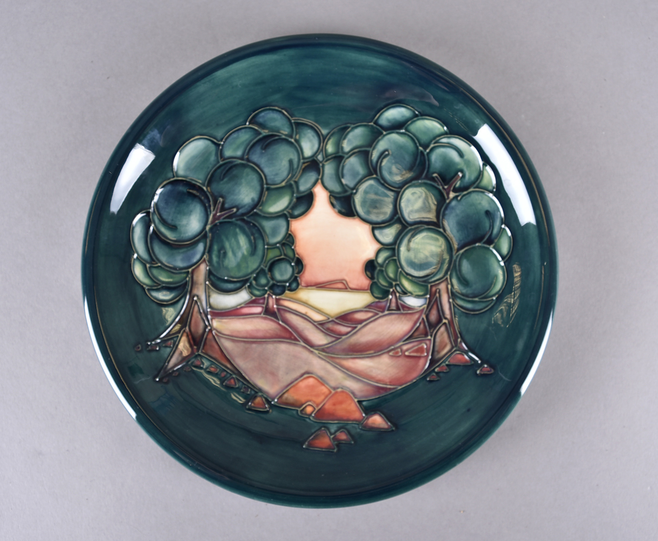 A modern Moorcroft plate, tubelined decoration trees in landscape, printed factory mark to