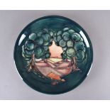 A modern Moorcroft plate, tubelined decoration trees in landscape, printed factory mark to